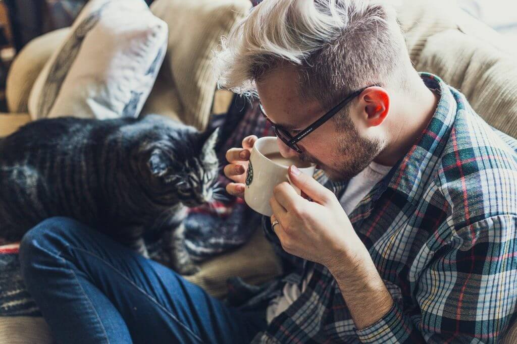 家のソファで寛ぎながらコーヒーを飲む男性